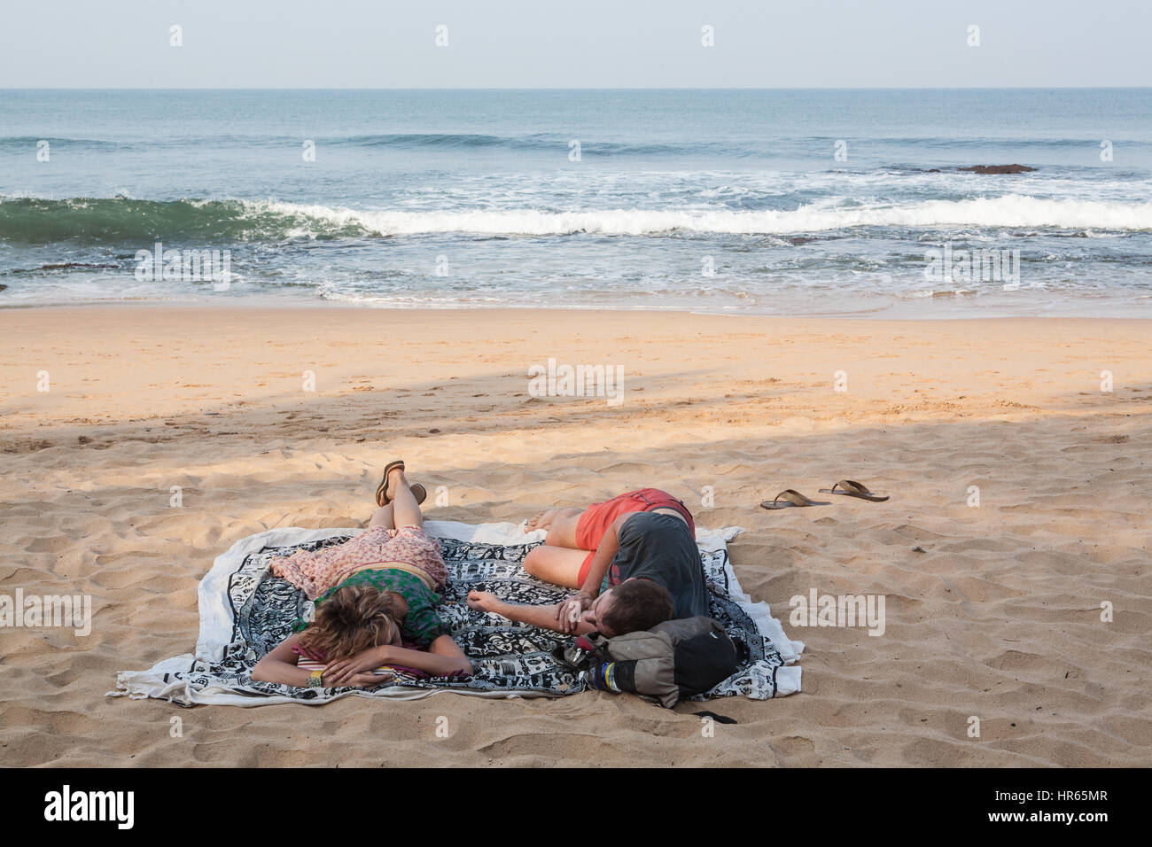 Two,Tourist,tourists,Couple,lack,of,sleep,deprived,deprivation,Sleeping,after,party,partying,late night,on,Anjuna,beach,Goa,India,Indian,Asia,Asian. Stock Photo