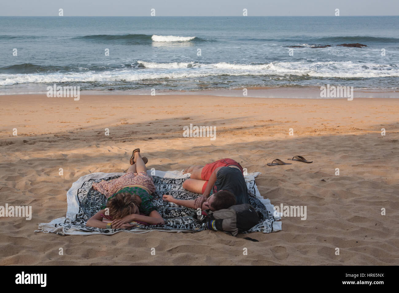Two,Tourist,tourists,Couple,lack,of,sleep,deprived,deprivation,Sleeping,after,party,partying,late night,on,Anjuna,beach,Goa,India,Indian,Asia,Asian. Stock Photo