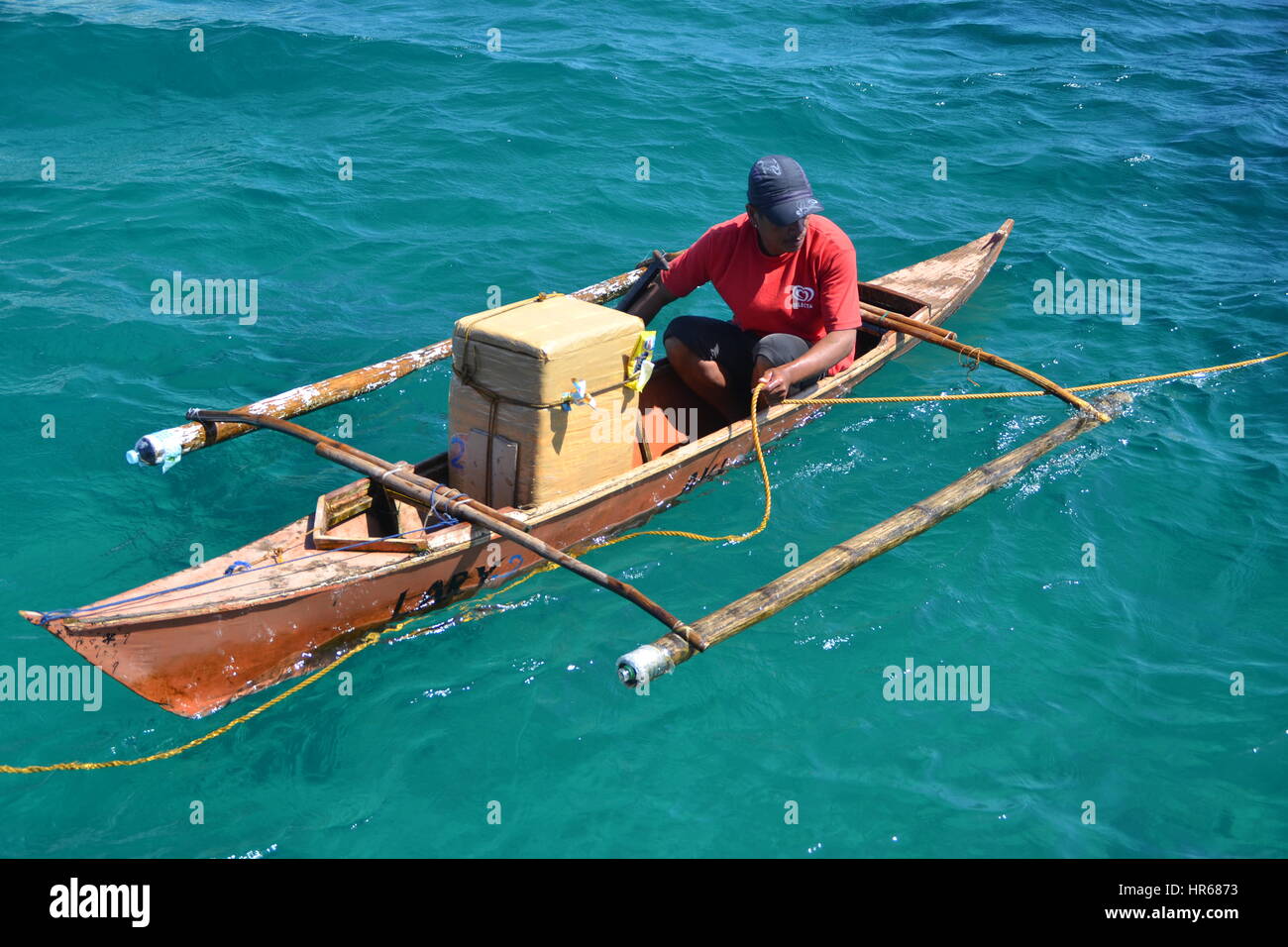 Man, sitting on simple wooden boat, big cardboard box, Boracay, Philippines. Stock Photo