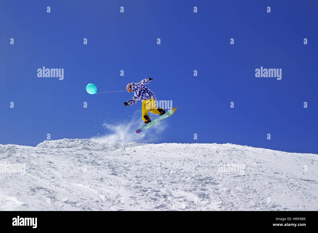 Snowboarder jump with toy balloon in terrain park at ski resort on sun winter day. Caucasus Mountains, region Dombay. Stock Photo