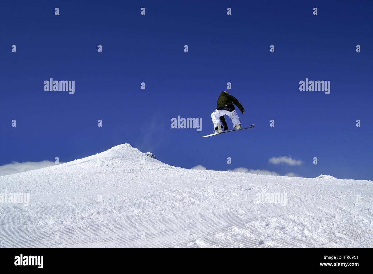 Snowboarder jump in terrain park at ski resort on sun winter day. Caucasus Mountains, region Dombay. Stock Photo
