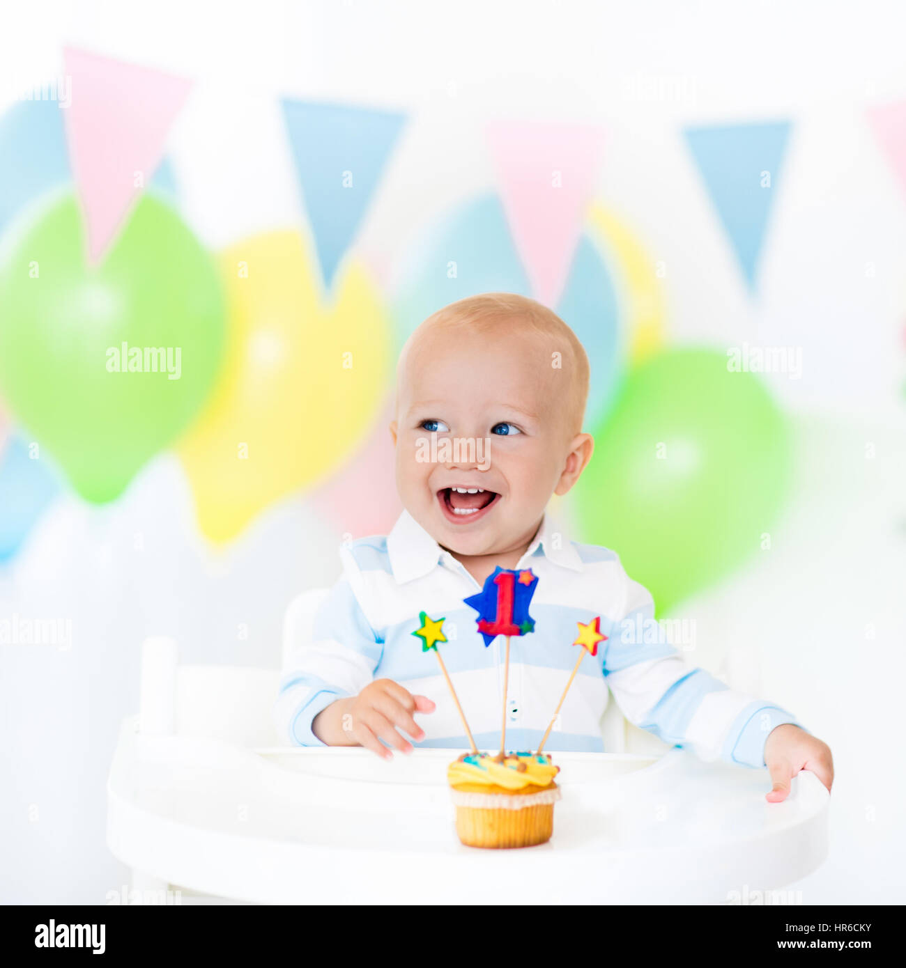 Adorable baby boy celebrating first birthday blowing candles on colorful  cup cake. Kids birthday party decorated with balloons and pastel color  banner Stock Photo - Alamy