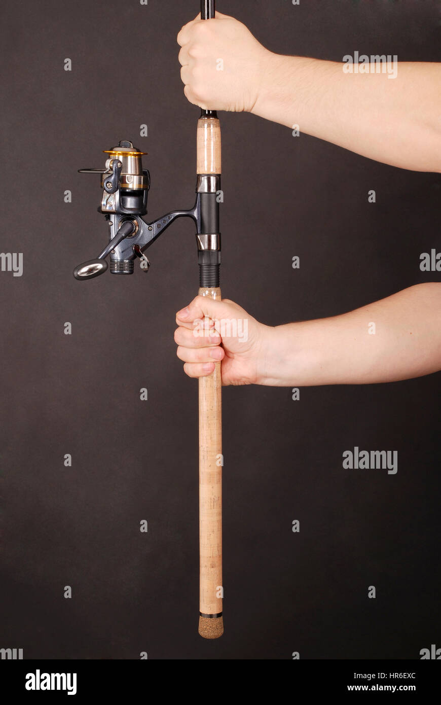 Man's hand holding a fishing rod on a black background Stock Photo