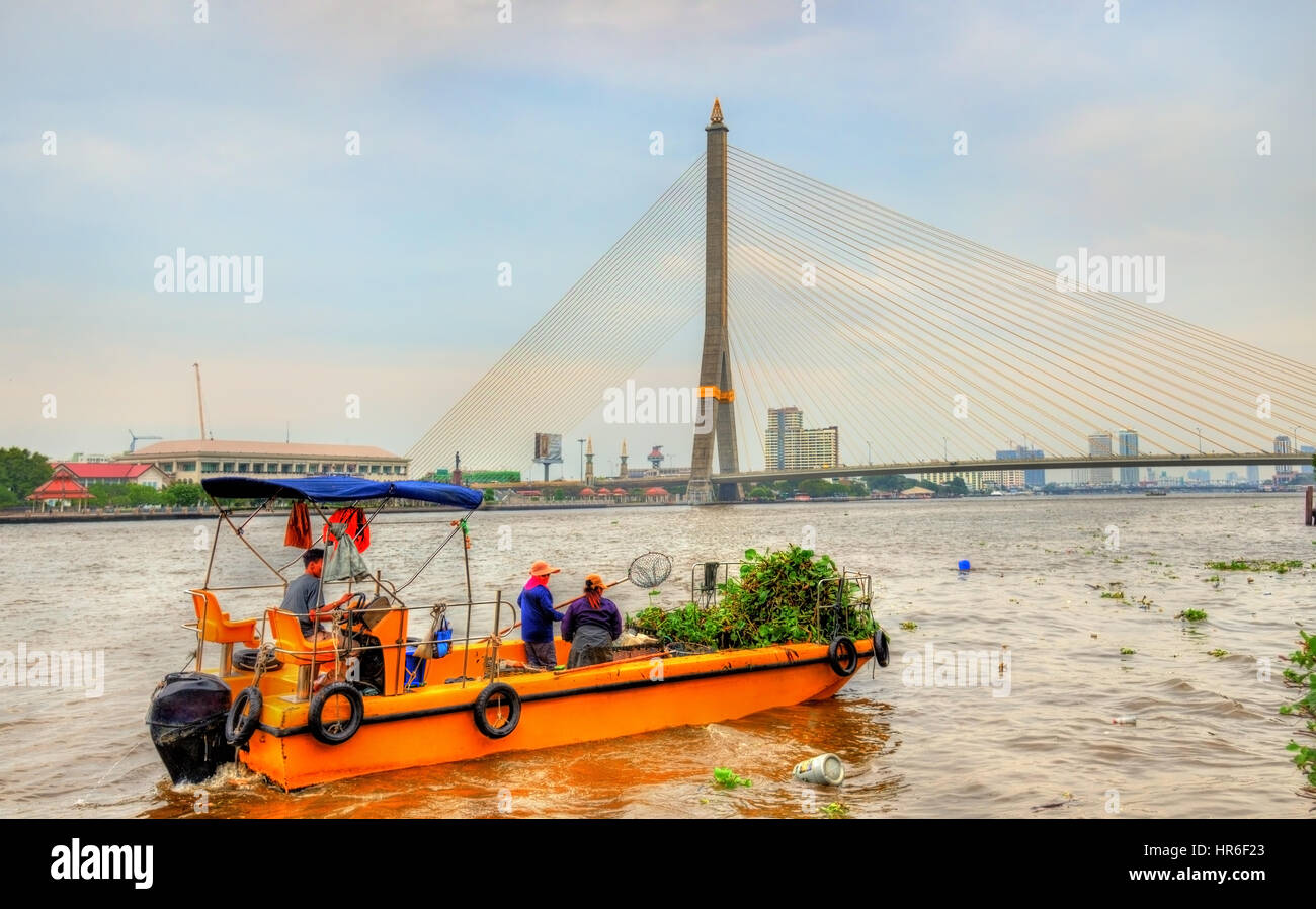Boat cleaning the Chao Phraya river in Bangkok, Thailand Stock Photo