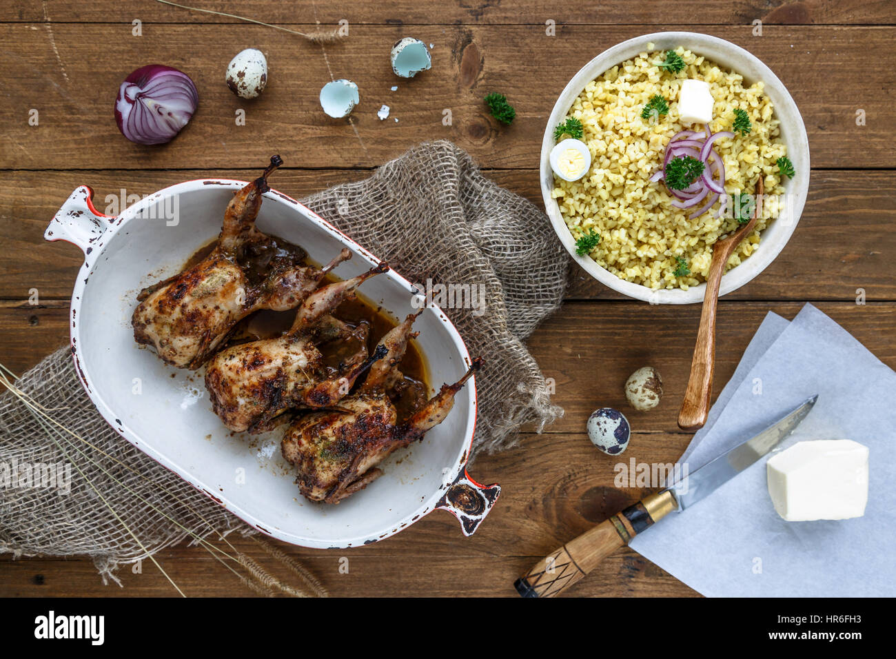Delicious fried quails with eggs with bulgur porridge on a wooden table, rustic style. Top view. Stock Photo