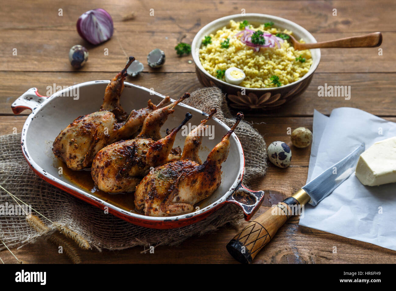 Delicious fried quails with eggs with bulgur porridge on a wooden table, rustic style. Top view. Stock Photo