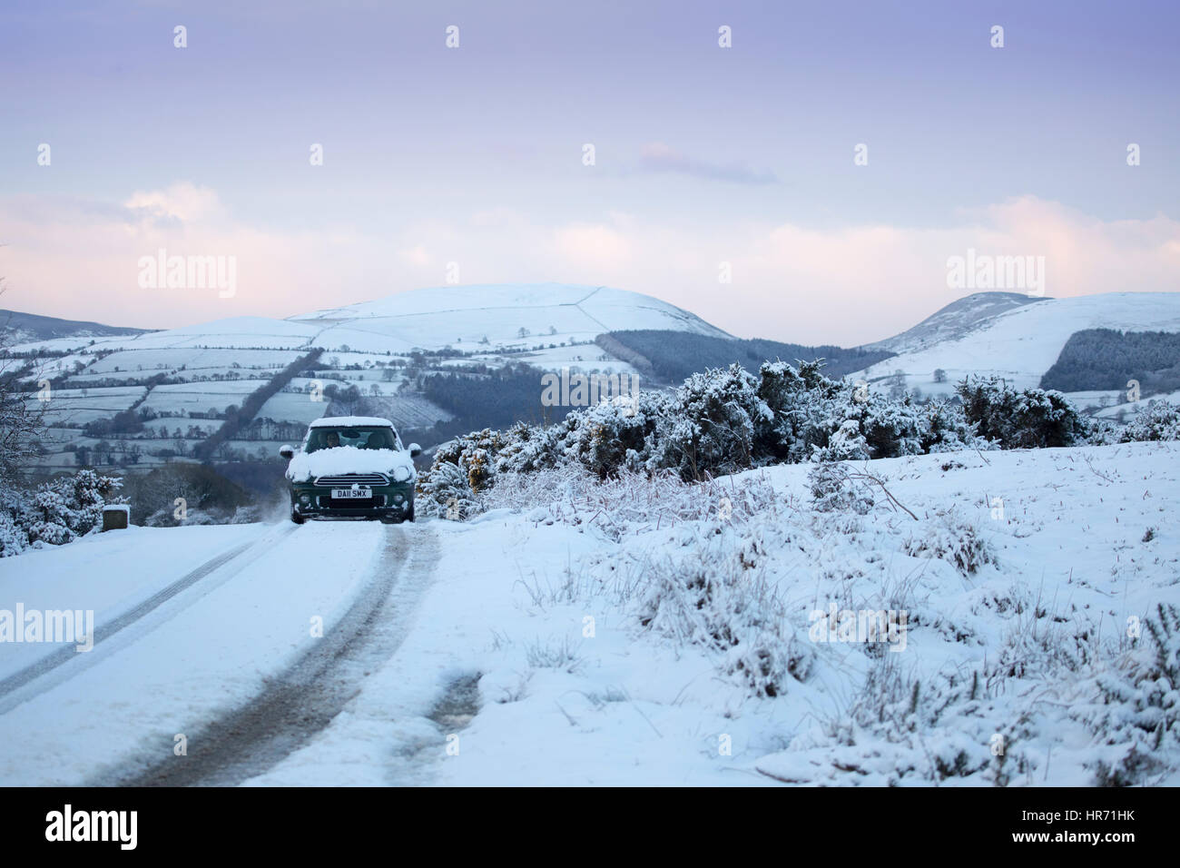 A car traveling down an isolated snow covered lane in rural Flintshire