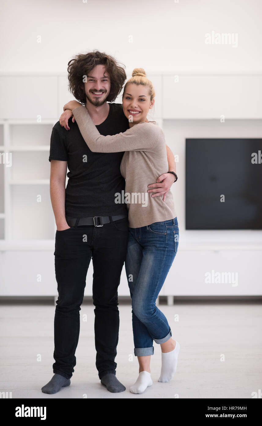 Portrait of a happy young beautiful couple hugging in their new home ...