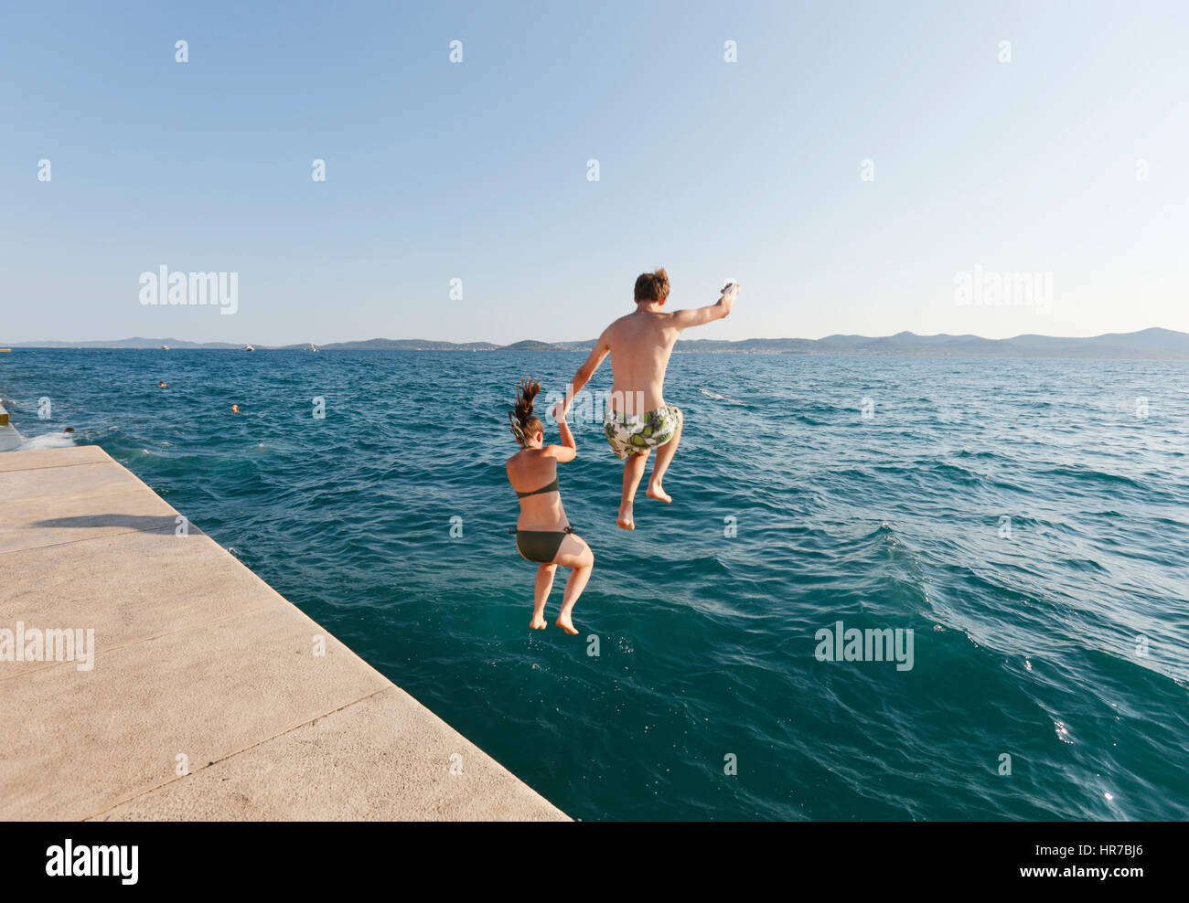 Young couple jump into the sea in Zadar Croatia Stock Photo