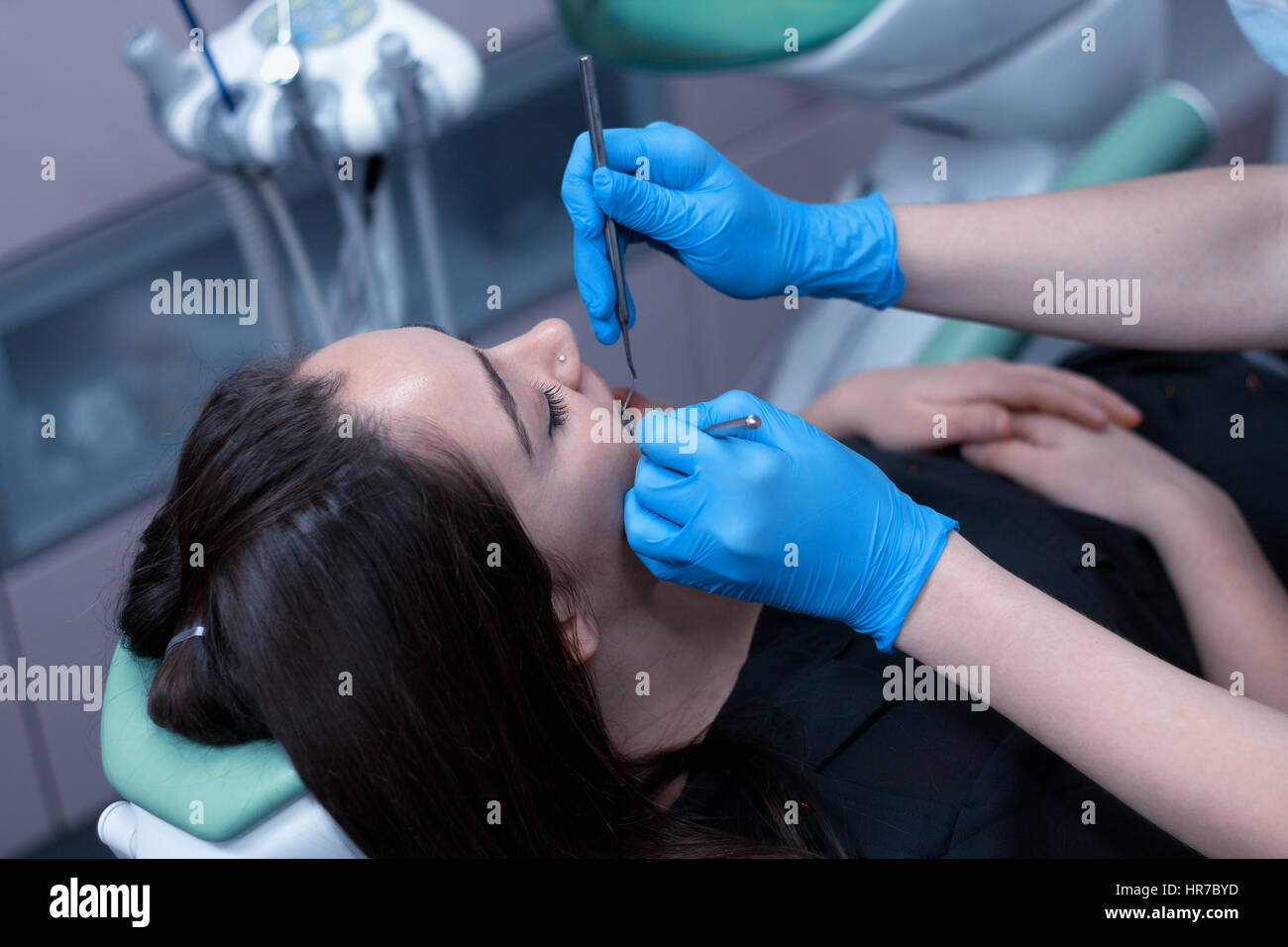 Dentist at work examining woman's teeth in dental clinic. Doctor is