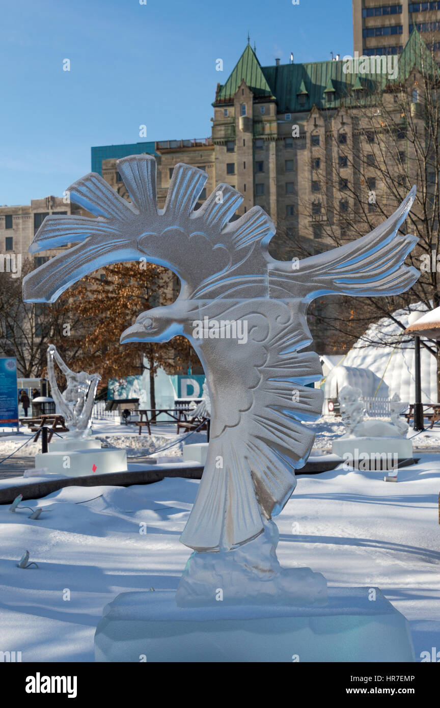 Ice sculpture in Ottawa, on a sunny day with city buildings behind. Carving  is of a large bird of prey, a crow, hawk or eagle with wings outstreched f  Stock Photo -