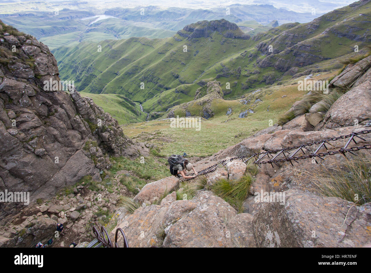A hiker navigates steep chain ladders to get up a cliff in Royal Natal National Park, South Africa on the Amphitheater Hike. Stock Photo