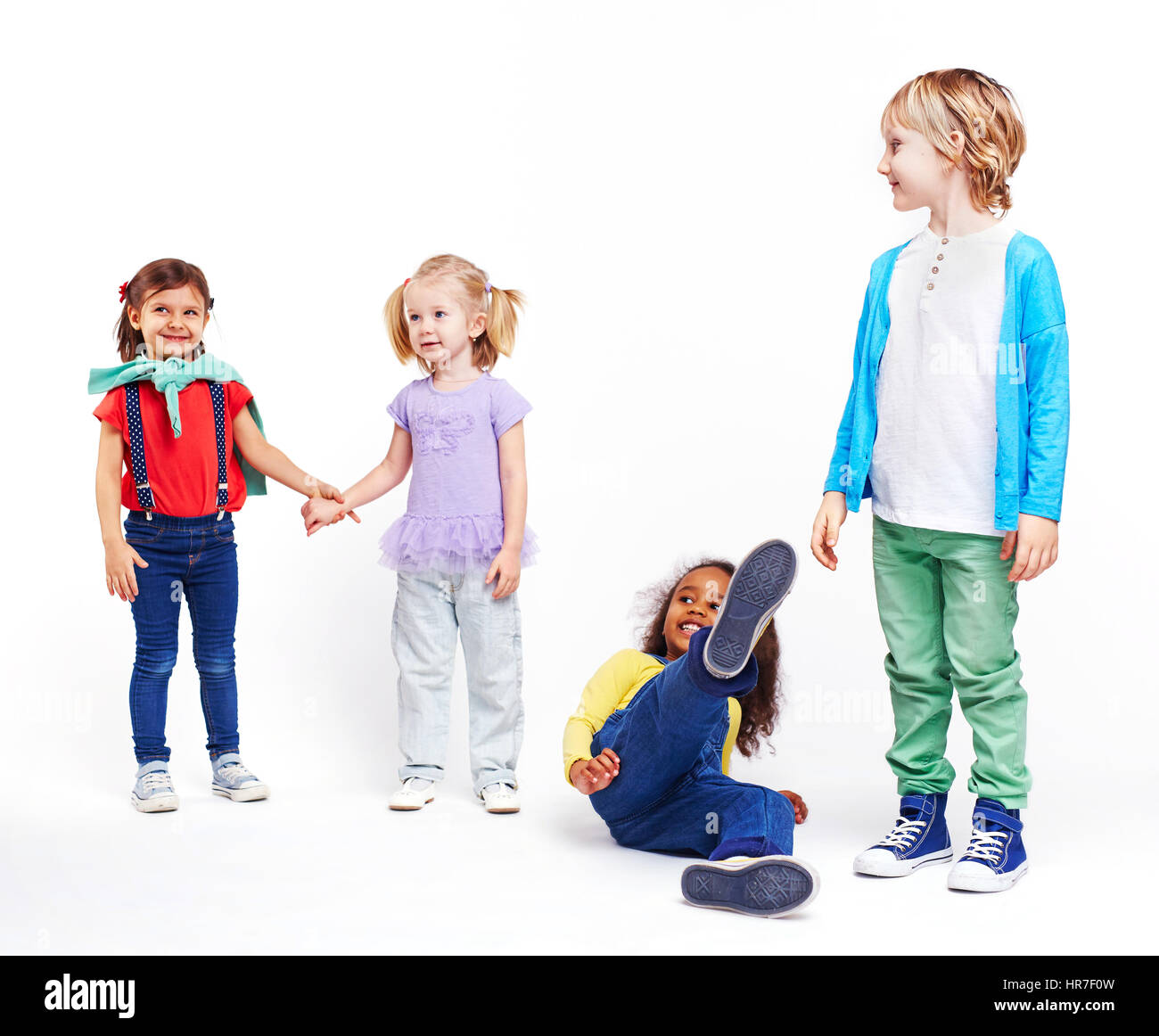 Studio portrait of children against white background: cutout of four kids in bright colorful clothes, two girls holding hands, girl falling down and b Stock Photo