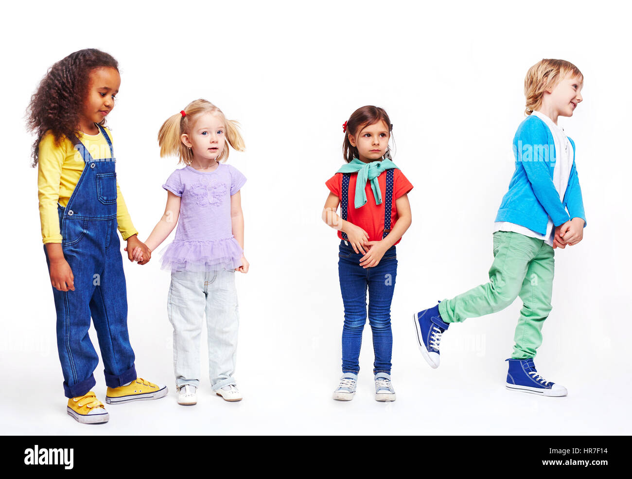 Studio portrait of children against white background: cutout of four kids in bright clothes, two girls holding hands, boy running and confused little  Stock Photo