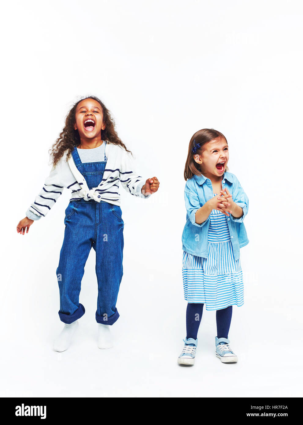 Full body portrait of two separate girls isolated on white, both dressed in colorful jeans clothes and screaming loudly with mouths open Stock Photo