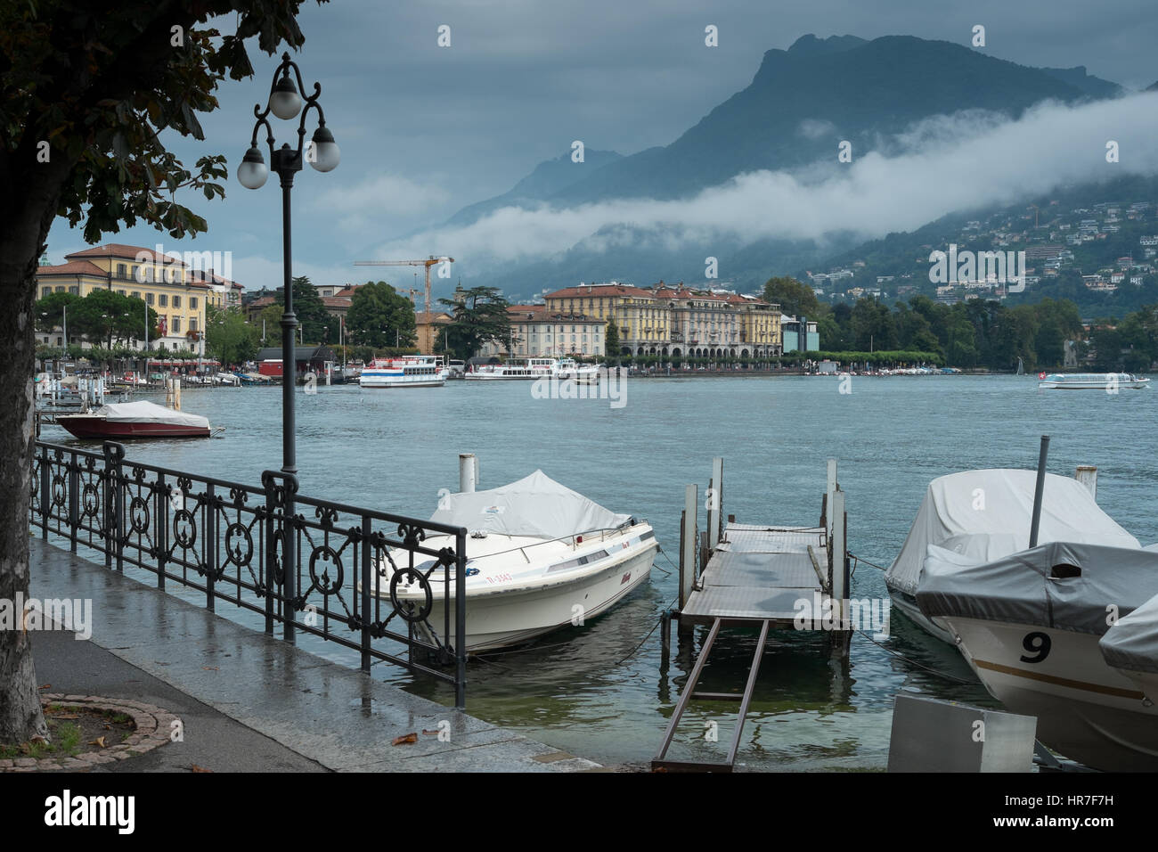 Motor Boats at the promenade of the luxurious resort in Lugano on Lake Lugano and Alps Stock Photo