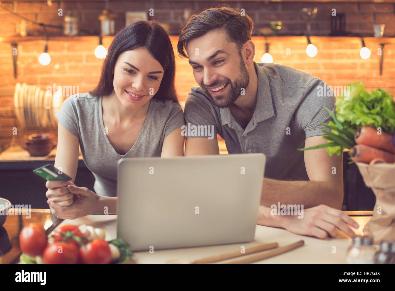 Order food online. Young beautiful couple in kitchen ordering food