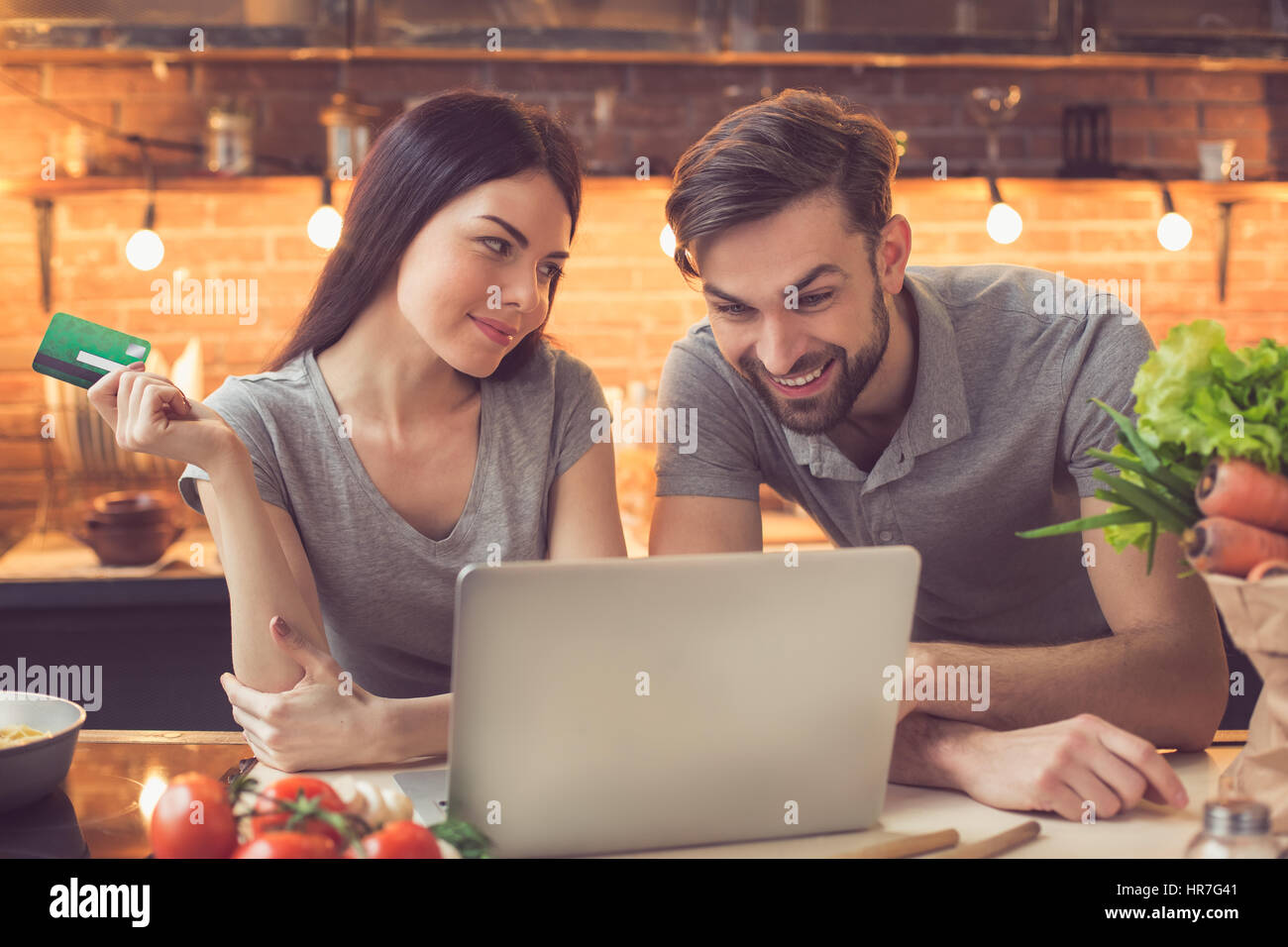 Order food online. Young beautiful couple in kitchen ordering food