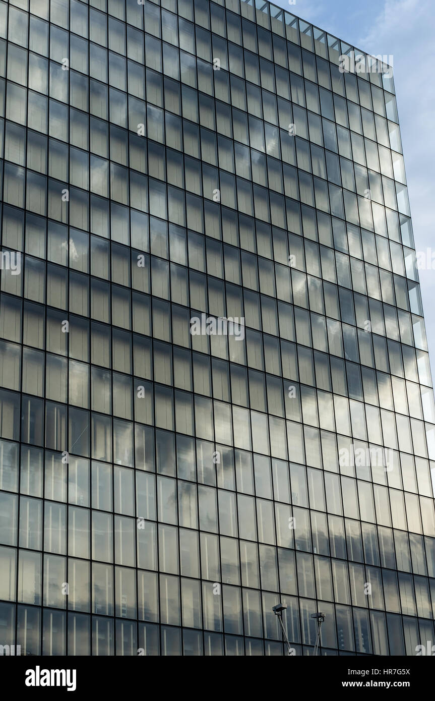 Facade of a glass high-rise building reflecting the dark clouds from ...