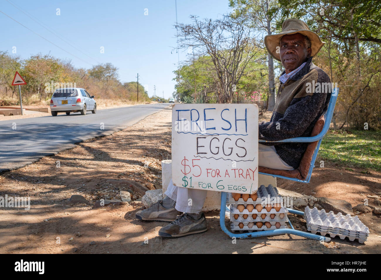 Old man selling eggs by the road. This man used to have his own touristic company but since the economic situation in Zimbabwe got more difficult ever Stock Photo