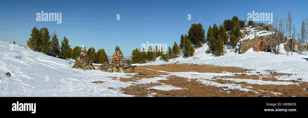 Pass in the mountains during the winter season. Pine trees, snow, rocks and dry yellow grass. Stock Photo