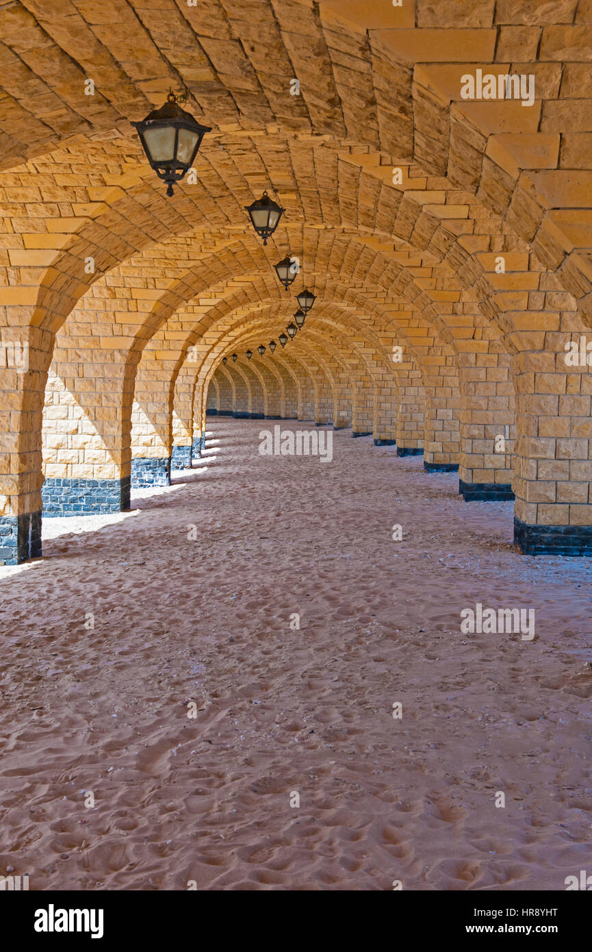 Underside of bridge with tunnel of arches curving to infinity on tropical beach Stock Photo