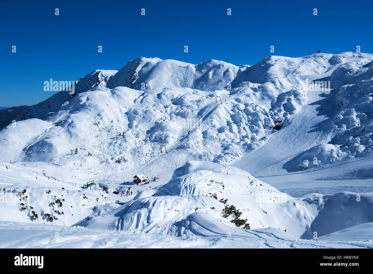 Ski slopes on snow capped mountain, bright sunny winter day with clear blue sky Stock Photo