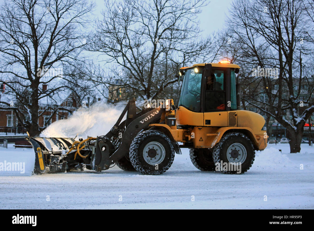 SALO, FINLAND - FEBRUARY 24, 2017: Unknown operator removes snow with Volvo L35B compact wheel loader equipped with snowplow on a winter evening in So Stock Photo