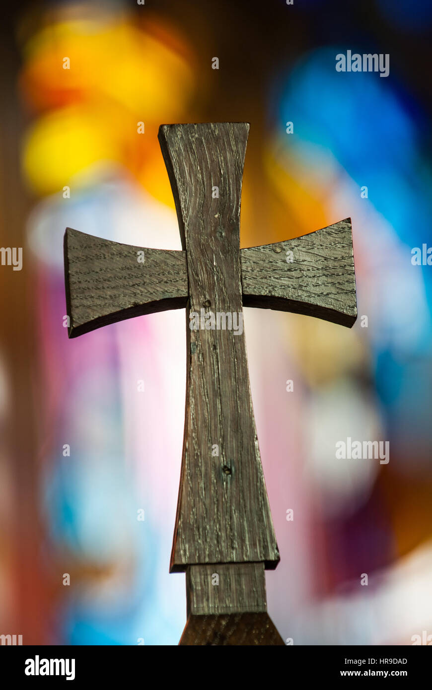 Religious cross against a blurred stained glass window. Stock Photo
