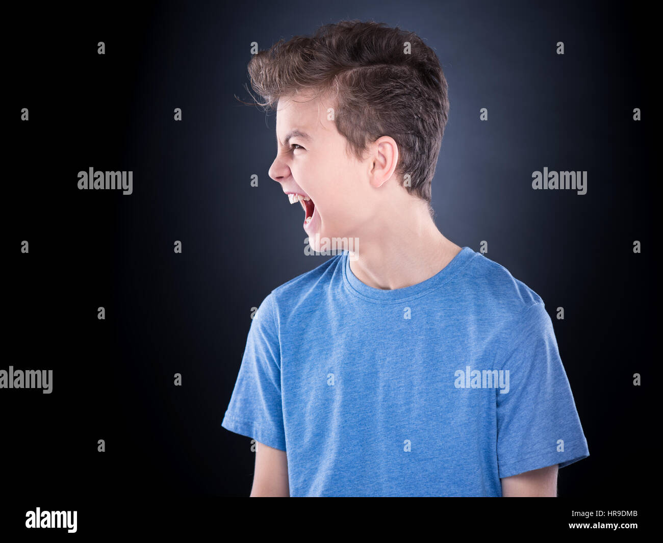 Emotional portrait of irritated shouting teen boy. Furious teenager screaming and looking with anger away. Handsome outraged child shouting out loud,  Stock Photo
