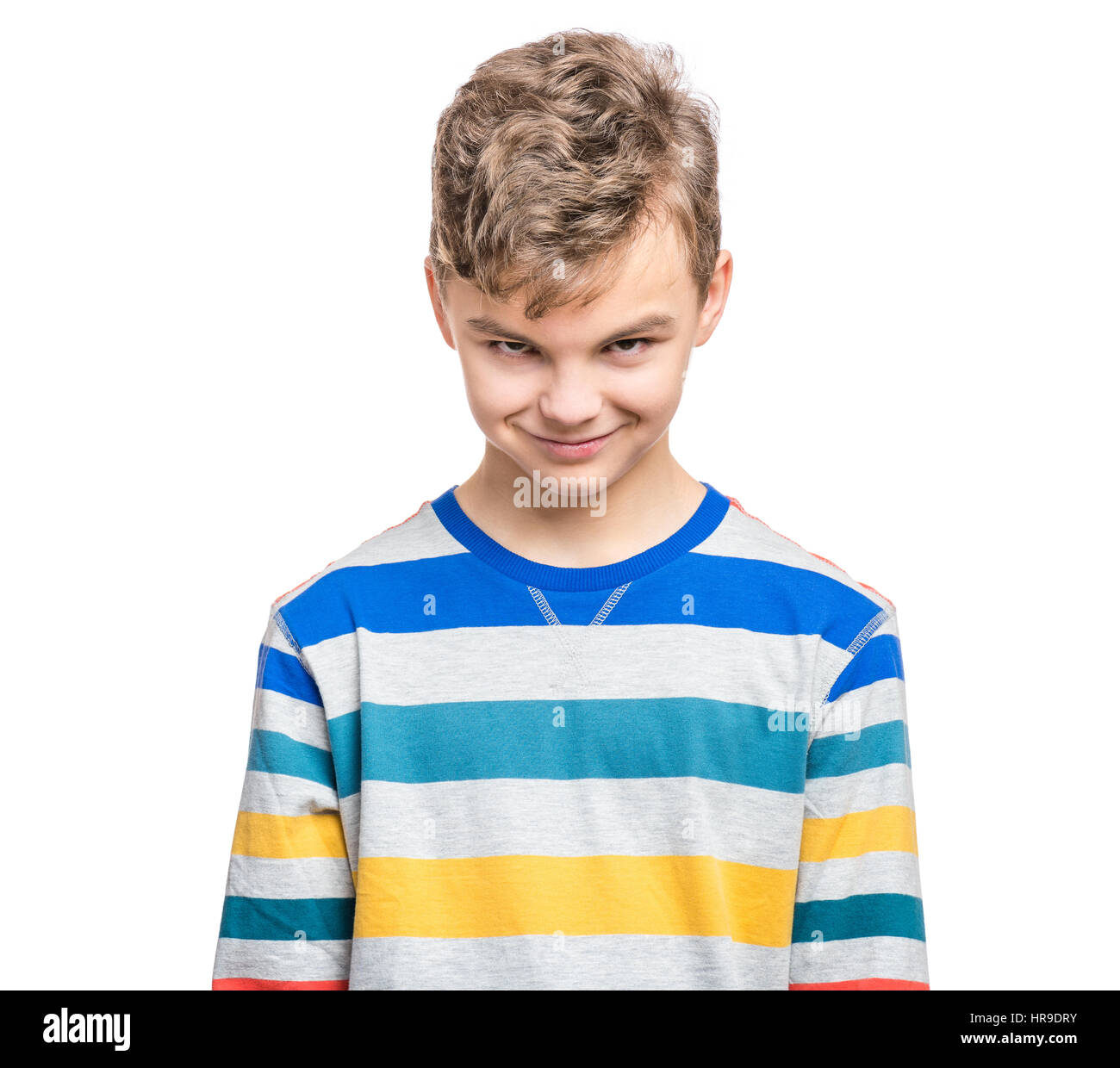 Teen boy making silly grimace - expressing cunning face. Upset child isolated on white background. Emotional portrait of caucasian teenager looking at Stock Photo