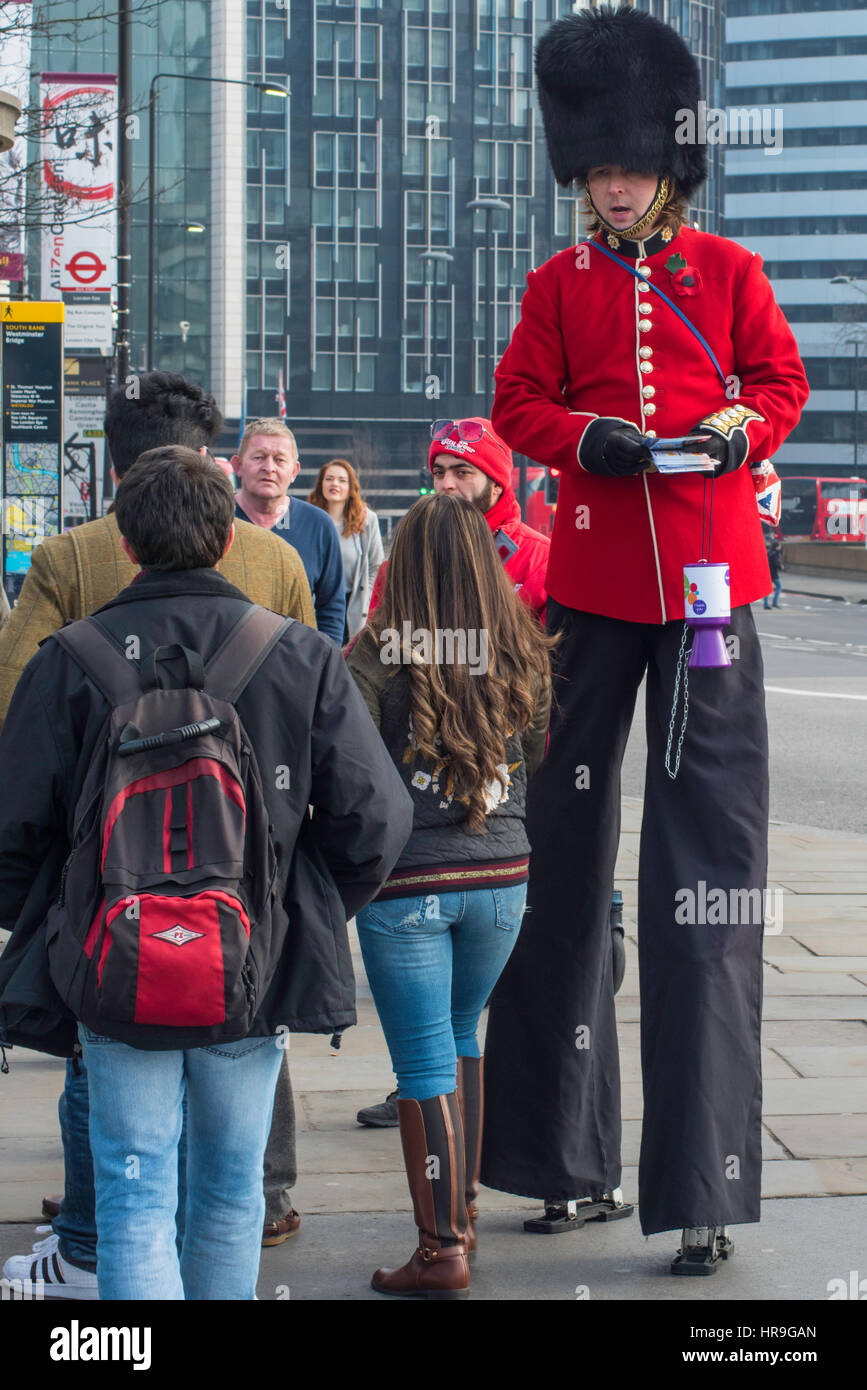 A man wearing stilts dressed as a Coldstream Guard soldier handing out