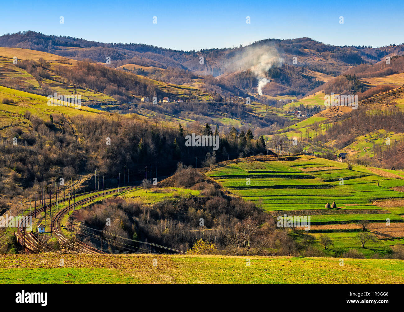 Spring time rural landscape. Railroad winds through agricultural fields in Carpathian mountains Stock Photo