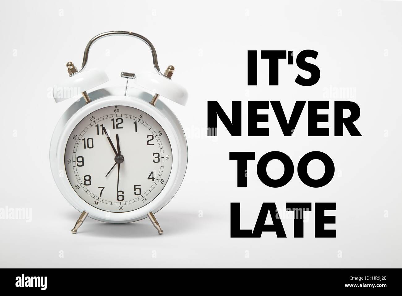 White old clock with text IT's NEVER TOO LATE Stock Photo