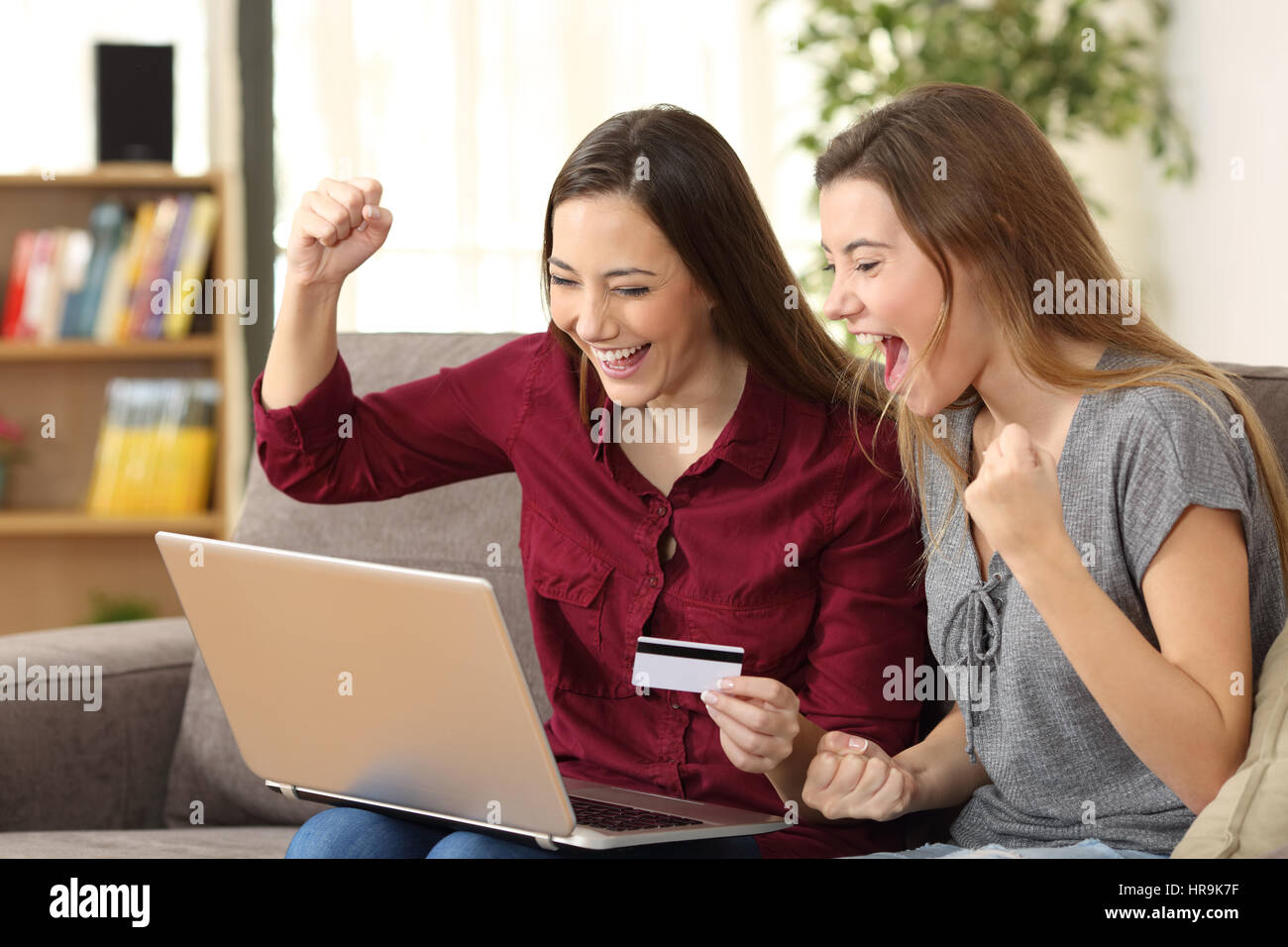 Excited roommates buying on line with credit card and a pc sitting on a