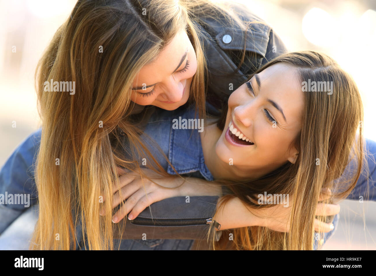 Two funny affectionate friends joking and laughing together in the street Stock Photo