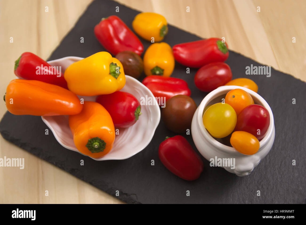 Cherry tomatoes and peppers mini, orange, red, yellow, Food photo with  vegetables in a layout with little peppers and tomatoes. Stock Photo