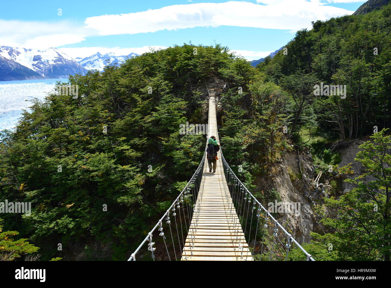 Unidentified backpacker crossing a suspension bridge in Torres de Paine National Park, Chile Stock Photo