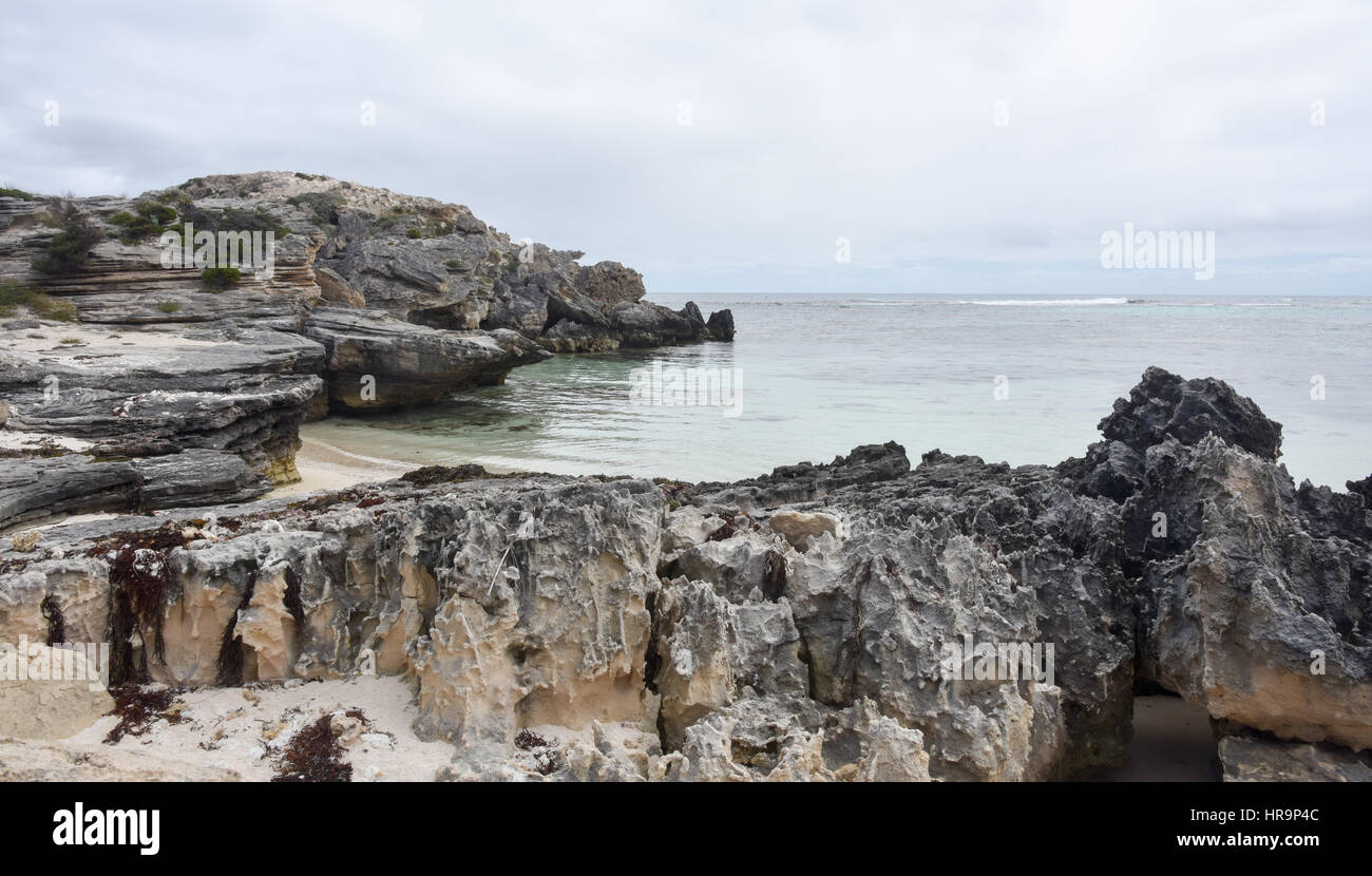 Grey, eroded limestone rock formations and remote Indian Ocean bay at ...