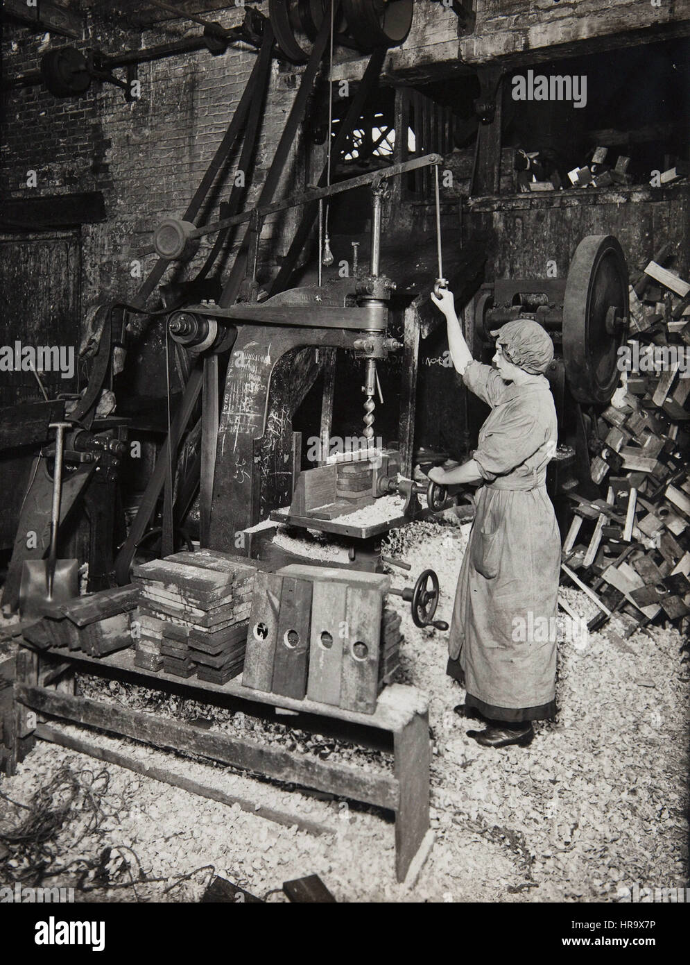 Woman operating boring machine; boring wooden reels for winding barbed wire Stock Photo