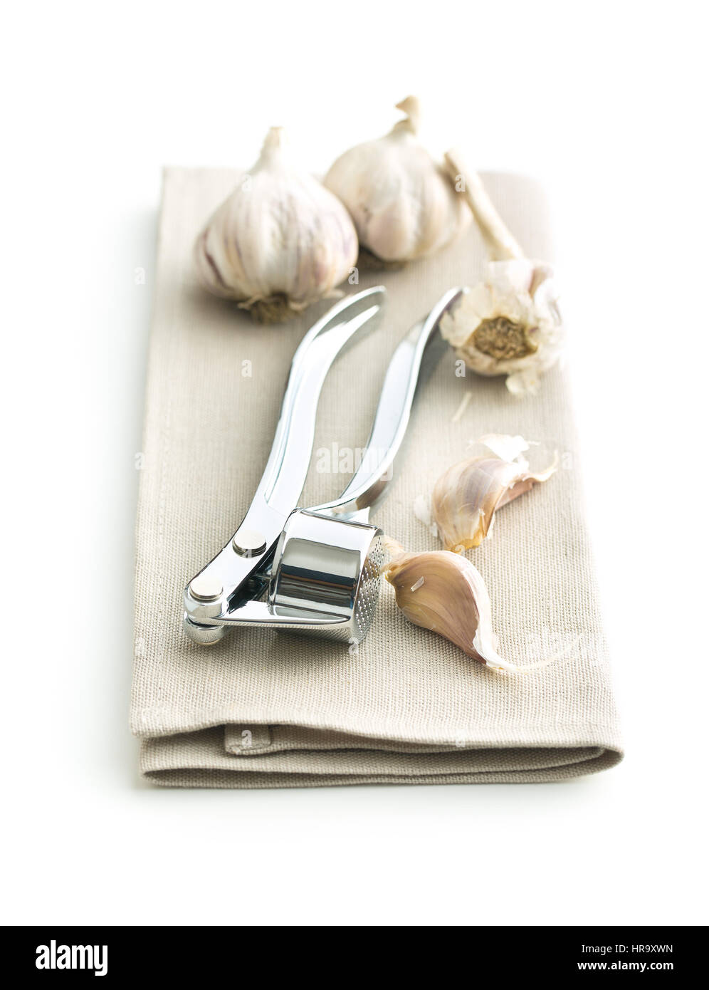 Garlic and garlic press on napkin isolated on white background. Stock Photo