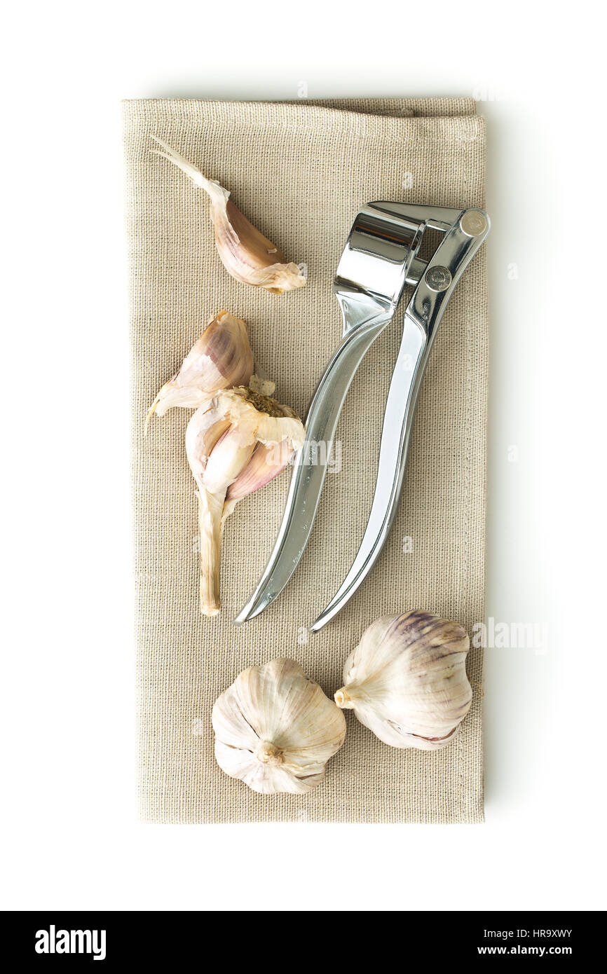 Garlic and garlic press on napkin isolated on white background. Stock Photo