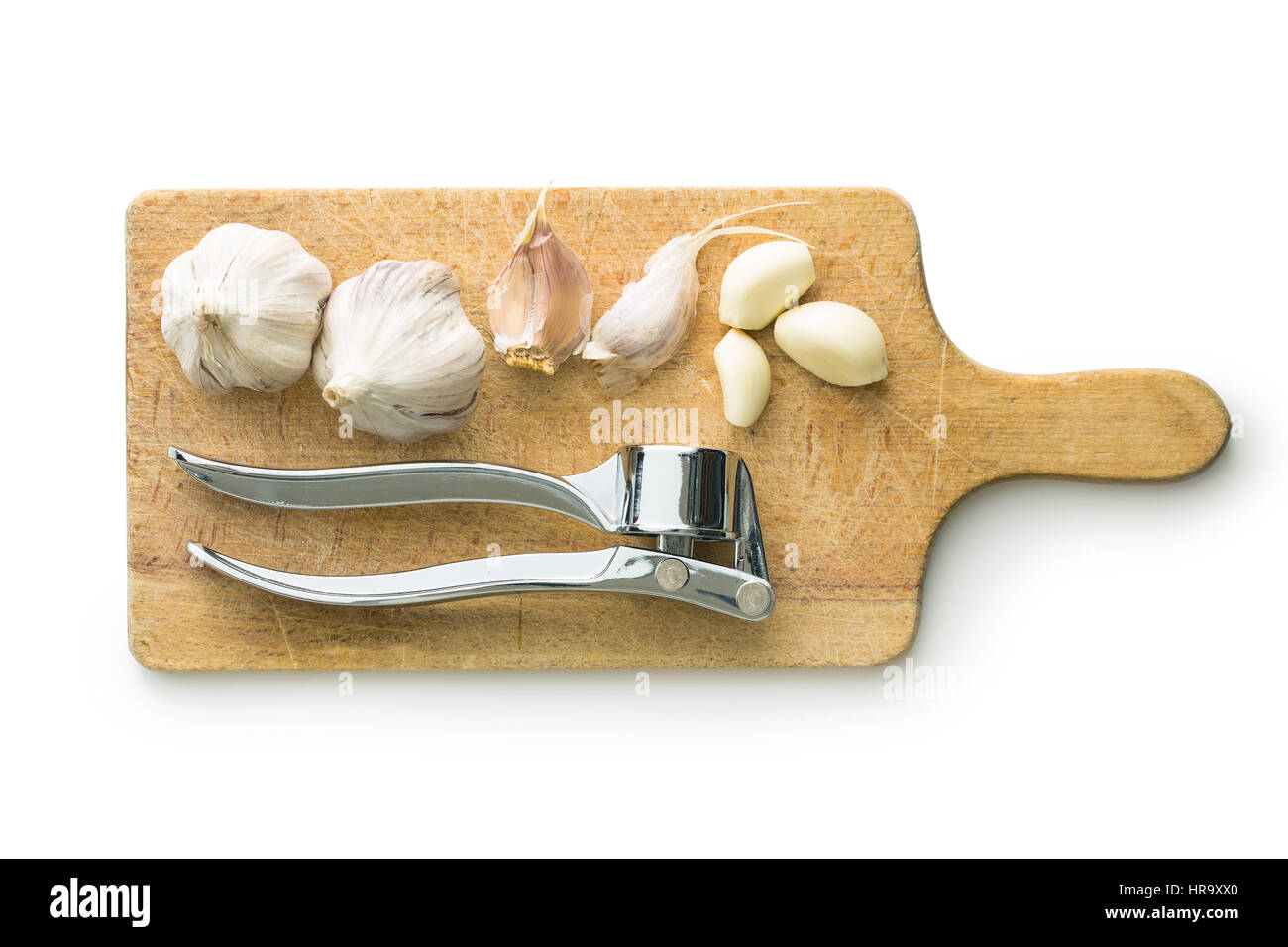 Garlic and garlic press on cutting board isolated on white background. Stock Photo