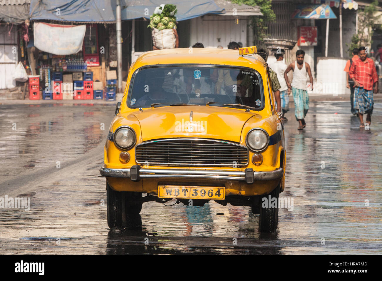 An Ambassador Yellow Cab Taxi Is Parked In The Street Under A Red Colored House In Kolcata India