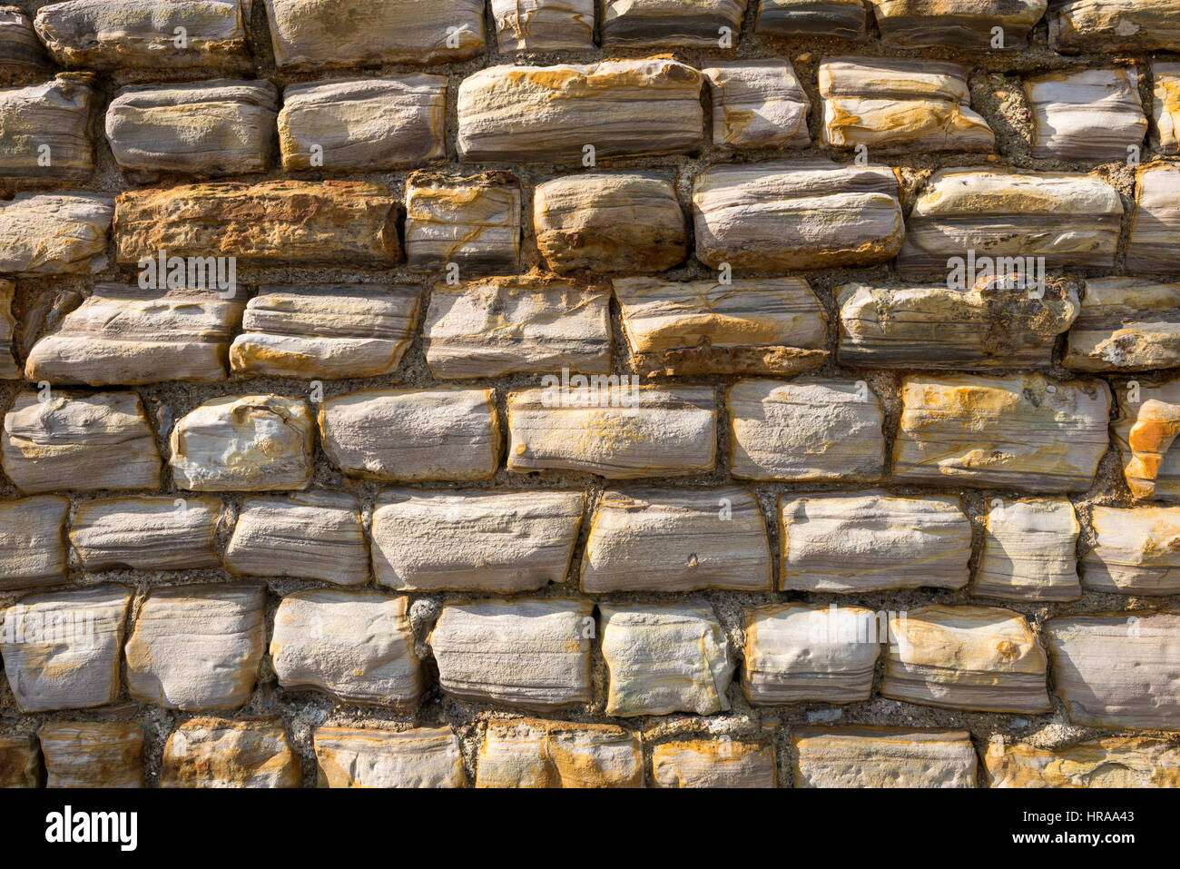 Close up of stone wall beside the beach at Scarborough. Warm coloured stones weathered by the sea. Stock Photo