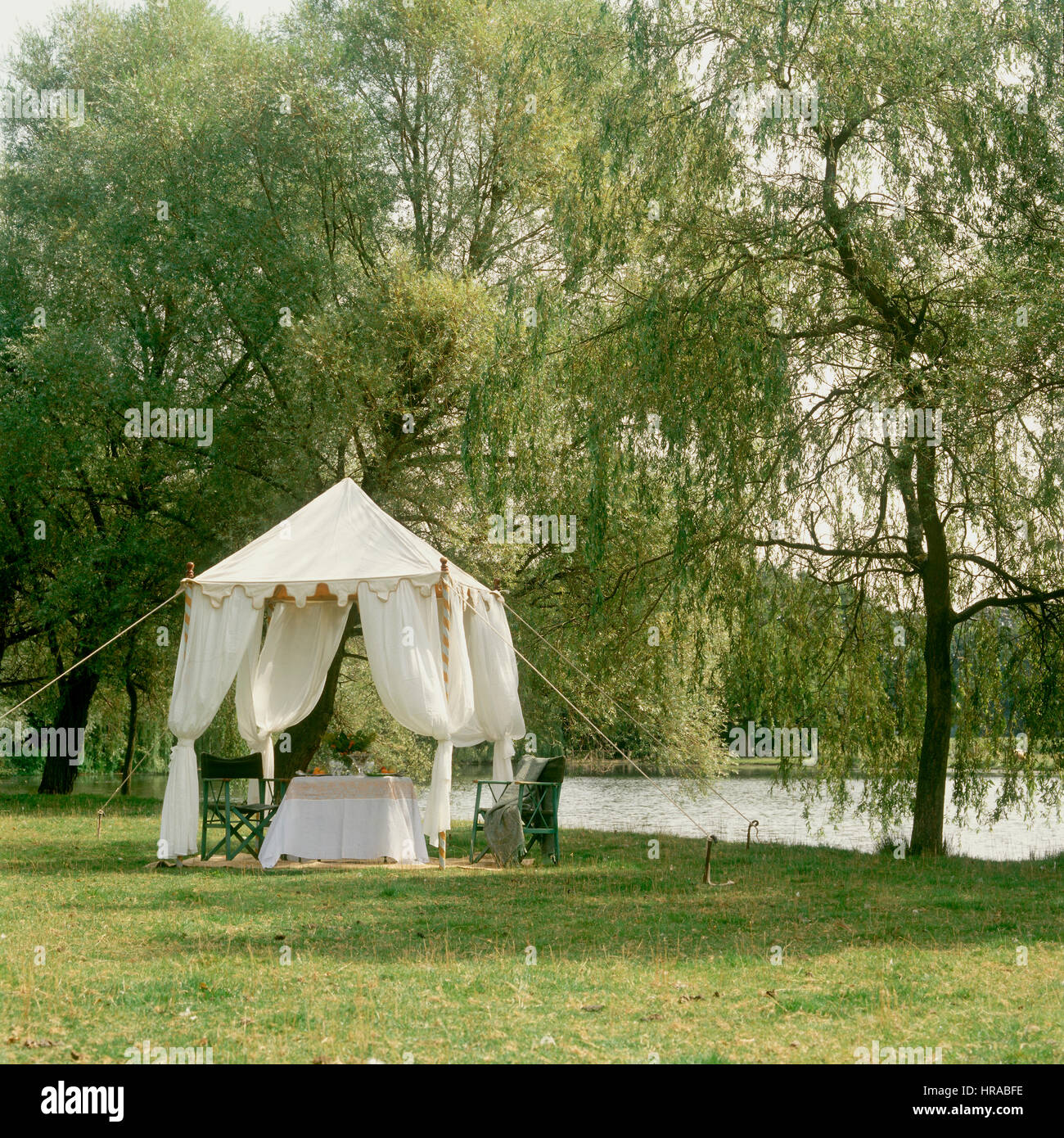 Tent with table and chairs by river. Stock Photo