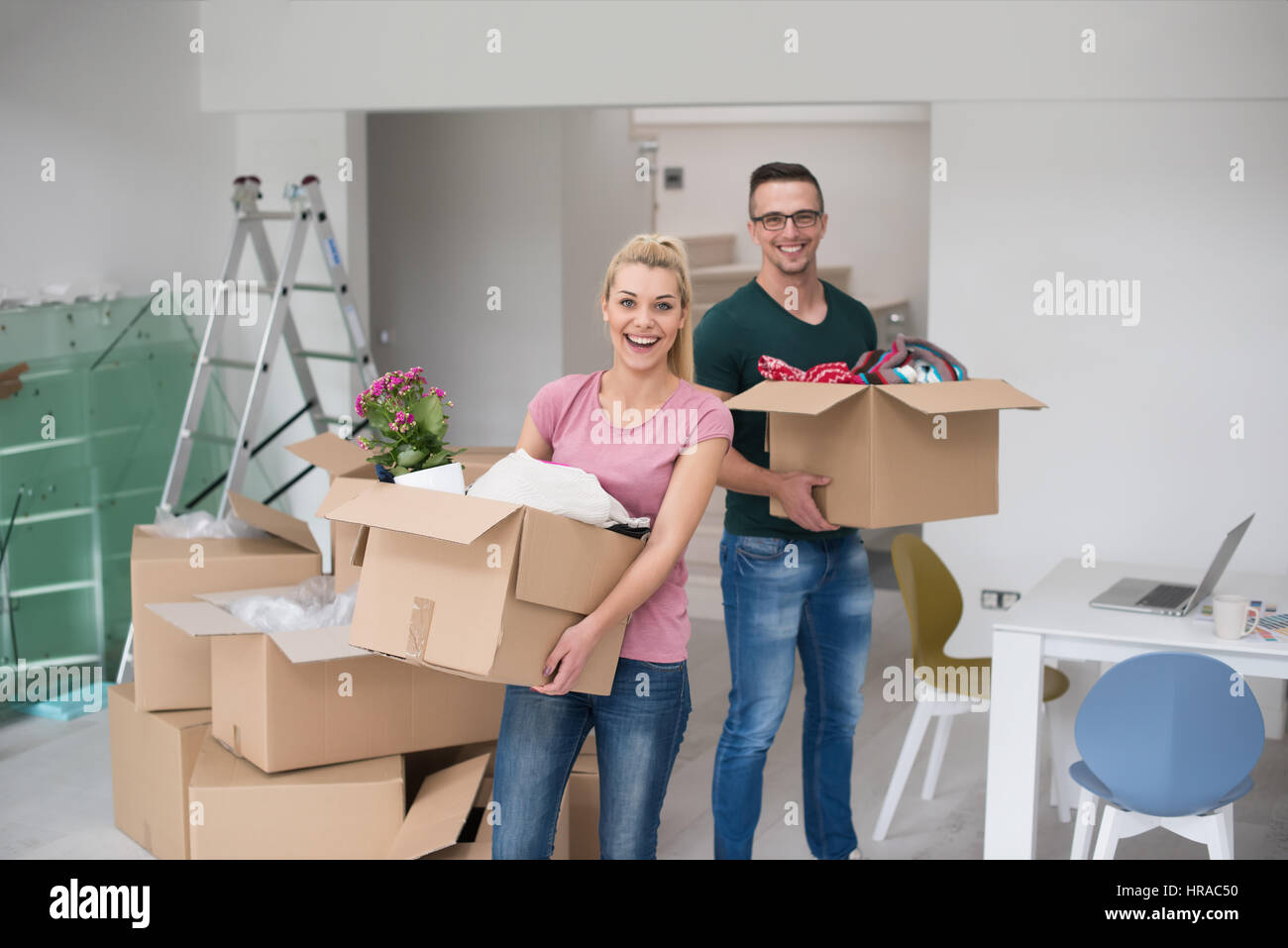 Happy young couple unpacking or packing boxes and moving into a new ...