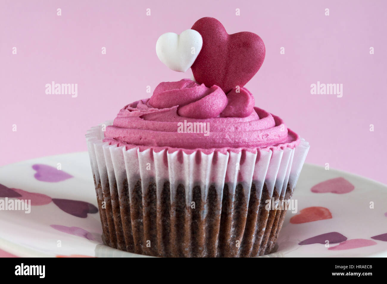 M&S Sweet Heart cupcake on hearts plate - moist Belgian milk chocolate chip cupcake filled with a raspberry sauce & loaded with a raspberry frosting Stock Photo