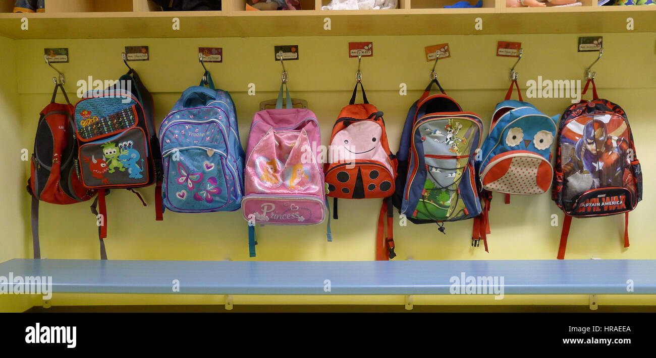 Childrens rucksacks hung on their pegs in a daycare Stock Photo