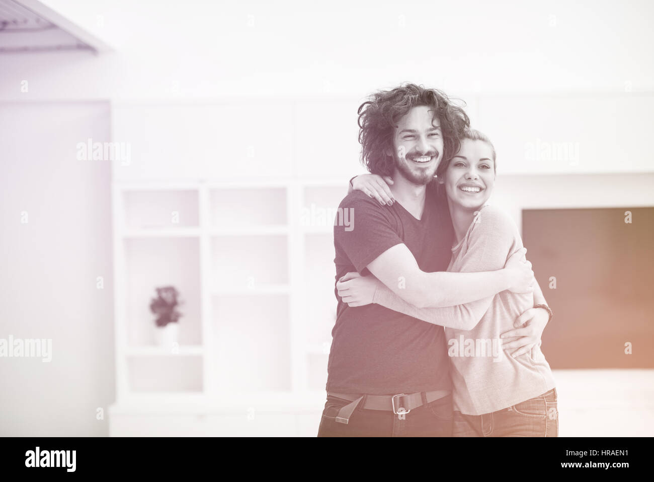 Portrait of a happy young beautiful couple hugging in their new home ...